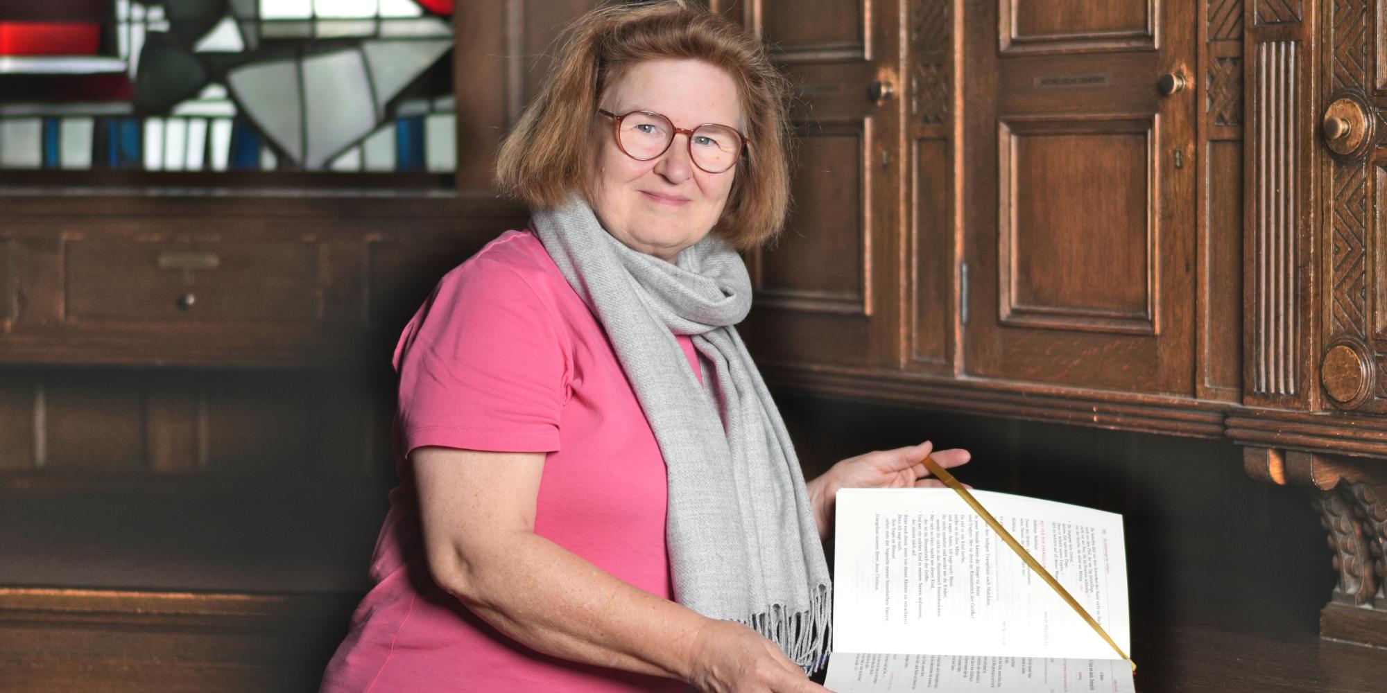 Renate Görtz schlägt ein liturgisches Buch in der Sakristei auf